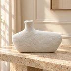 Off-white textured asymmetric pebble decor vase, styled on a travertine console