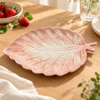 Berry Bloom blush leaf plate styled on a wooden table with fresh strawberries