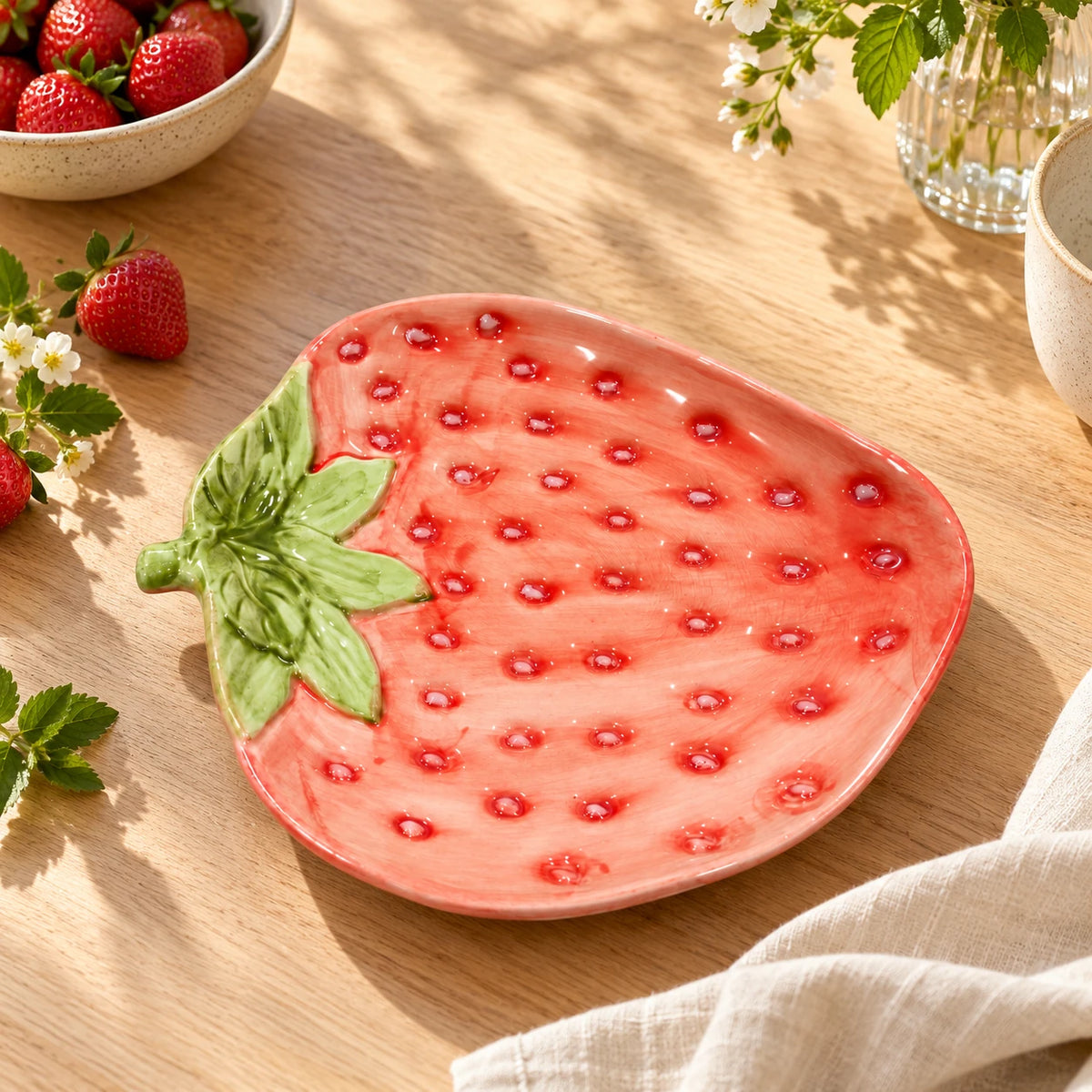 Berry Bloom strawberry-shaped plate styled on a wooden table with fresh strawberries