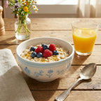 Bowl of oatmeal with berries and a glass of orange juice on a wooden table.